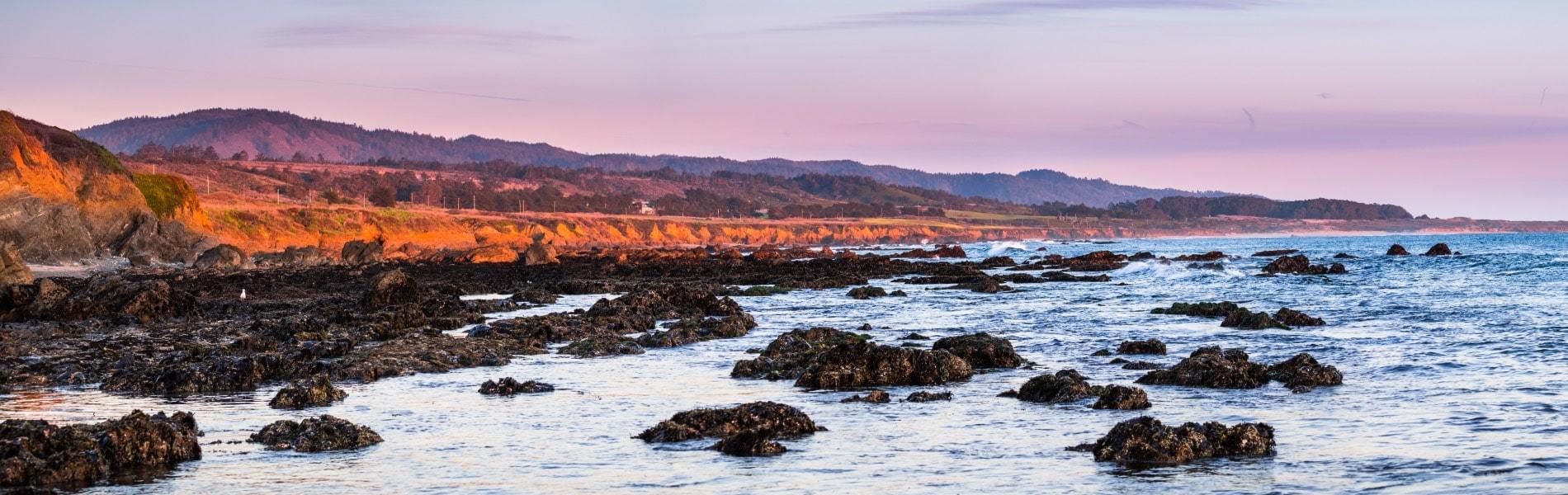 Sunset view of rocks and beach in Cliffwood Heights, California
